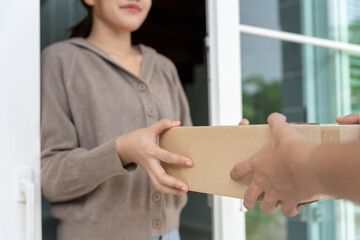 Happy smiling woman receives boxes parcel from courier in front house. Delivery man send deliver...