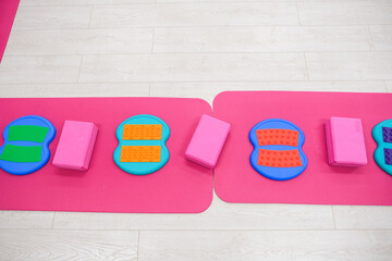 Bright yoga mats with colorful massage balance boards and pink blocks. Exercise equipment for toddler play.