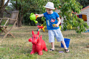 Junge spielt im Garten mit Wasser und Waschlappen