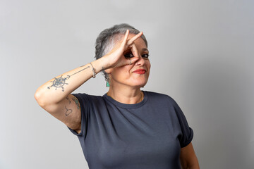Senior woman making ok sign with hand tattooed arm