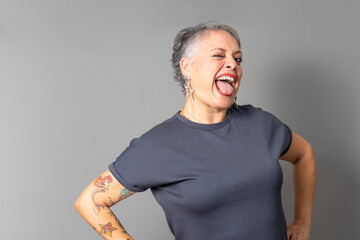 Playful senior woman sticking out tongue and winking in studio