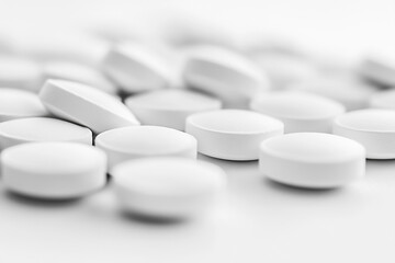 A close-up, low-angle shot of numerous pills scattered on a flat surface, with a shallow depth of field creating a soft, blurry background.
