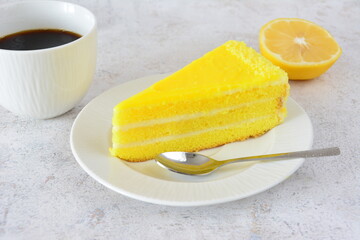 a Slice of lemon cake  on a saucer with a cup of Coffee and Lemon fruit