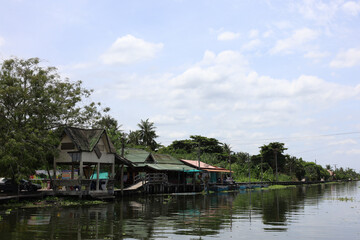 Tranquil Riverside Life: Traditional Stilt Houses on a Canal in Thailand