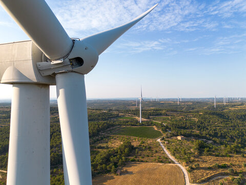 Close-up of wind turbine blades in Terra Alta, Catalonia, Spain, with rows of turbines on the horizon, highlighting renewable energy, sustainability, and innovation.                         