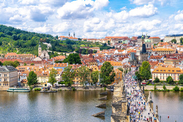 Prague from above the historic quarters of Mala Strana, Charles Bridge, and the calm waters of the Vltava River framed by summer greenery and a blue sky.Prague,Czech Republic