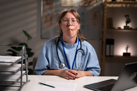 nurse working overtime on night shift makes fish lips show emotions tries, in hospital office. Health care and medicine service