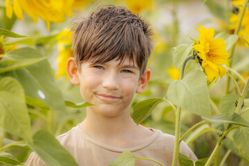 Peaceful boy with closed eyes gently smelling a bright sunflower, enjoying the beauty and calmness...