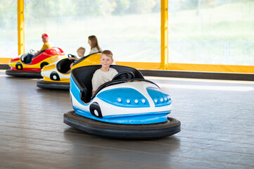 Teen boy riding bumper car at amusement park, fun and summer entertainment concept