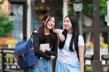 Two asian female students walking together and talking in university campus after class, friendship and lifestyle concept