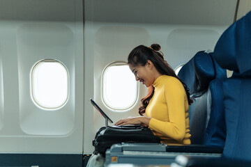 Happy businesswoman using tablet while traveling by airplane, enjoying work and connectivity during...