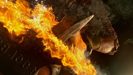 Close-up of blacksmith forging glowing hot iron on anvil with flying sparks