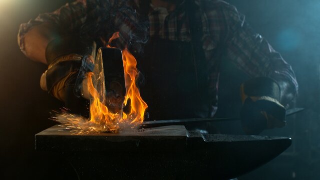 Close-up of blacksmith forging glowing hot iron on anvil with flying sparks - Powered by Adobe