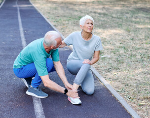 Active mid age senior mature couple jogging together, helping and supporting each other with a...