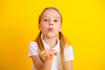 Charming schoolgirl blowing a kiss against a vibrant yellow background showcasing joy, childhood innocence, and colorful education themes