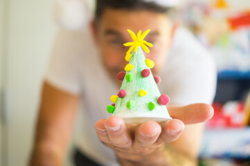 Out of focus person holding a Christmas tree made from recycled material