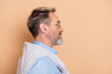 Profile portrait of mature businessman with trendy glasses and beard against beige background...