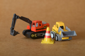 Fototapeta premium Heavy Equipment at Work: Orange Excavator and Yellow Loader in a Miniature Construction Zone.