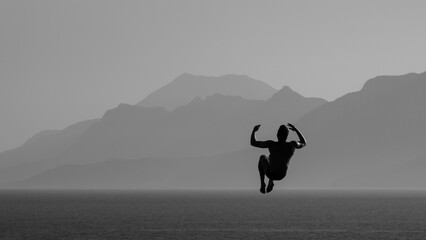 man jumping off rock into sea