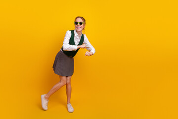 Smiling schoolgirl wearing stylish uniform posing confidently against yellow background, showcasing...