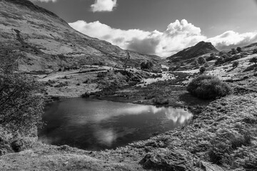 Monochrome mountain landscape with small lake and clouds