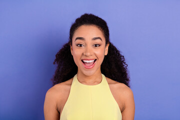 Young woman with a captivating expression wearing a stylish yellow outfit against a vibrant purple...