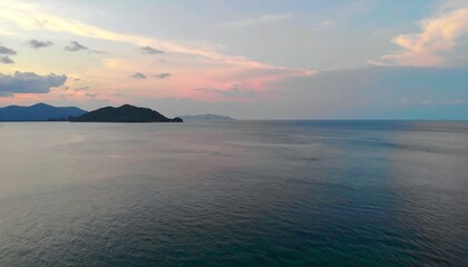 Serene sunset over calm ocean waters, distant islands silhouetted against a pastel sky