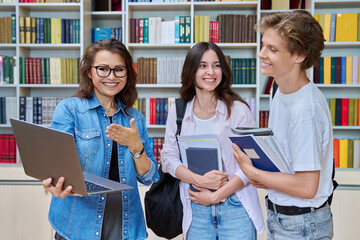 Two teenage students meeting talking with female teacher in library