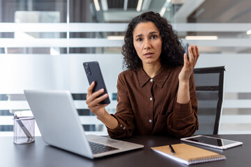 Businesswoman puzzled while using smartphone during office work