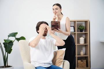 Dreams come true. Woman giving man gift box at home