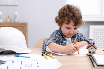 Choice of profession. Little kid with divider and engineering drawing at table indoors
