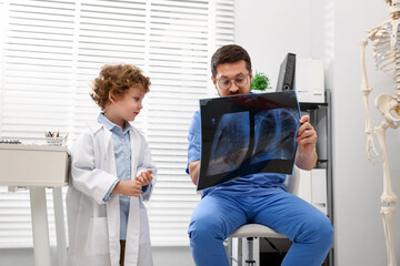 Choice of profession. Father and his son examining X-ray picture in clinic