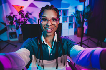 Vibrant young woman in neon-lit home office setting showcasing creativity and enthusiasm for streaming and podcasting