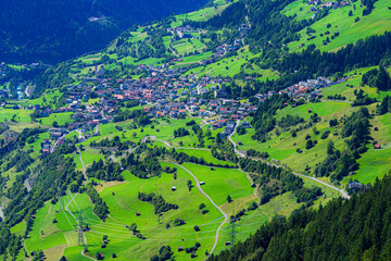 Blick hinunter auf die Stadt Flie&szlig; im Inntal, umgeben von sommerlichen, fruchtbaren Weidefl&auml;chen und Waldst&uuml;cken;  &Ouml;sterreich, tirol