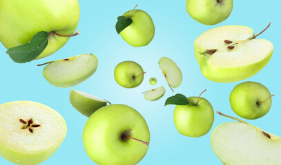 Fresh green apples swirling in air against light blue background
