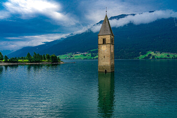 mystische Szenerie am Reschensee mit dem aus dem Wasser ragenden Kirchturm des versunkenen Dorfes...