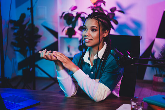 Podcaster female content creator recording a podcast at home with professional equipment under vibrant neon lighting