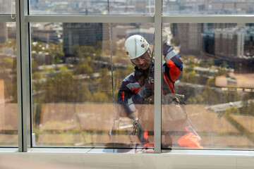 Man industrial climber or window cleaner on a rope washing skyscraper windows.