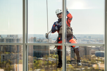 Man industrial climber or window cleaner on a rope washing skyscraper windows.