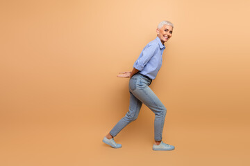 Elderly businesswoman posing confidently in trendy casual clothing against a beige studio background