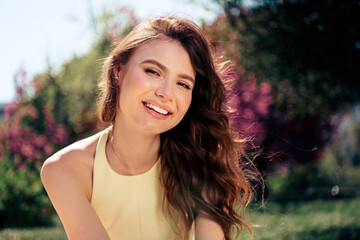 Lovely woman in yellow dress basking in the sunlight outdoors, showcasing her bright smile and...