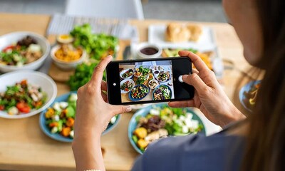 Person taking photo of diverse food dishes on table