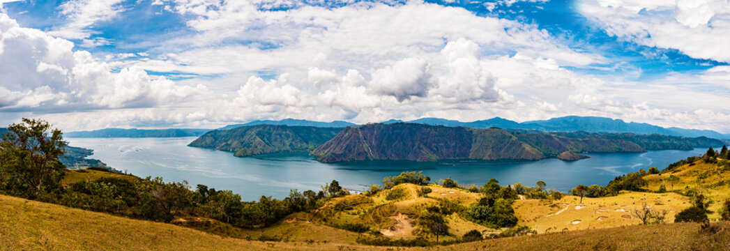 Panoramic view of Lake Toba from Sibea-bea Hill in Samosir, North Sumatra, Indonesia. The breathtaking landscape features the vast volcanic lake surrounded by lush green hills and mountains, showcasin