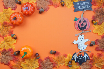 Top view of Halloween border with autumn leaves, acorns, pumpkins, ghost, bat, and 