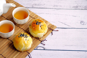 Mooncakes (Egg yolk cake) and teapot on wooden table and autumn decoration. Mid-Autumn Festival background. Copy space.