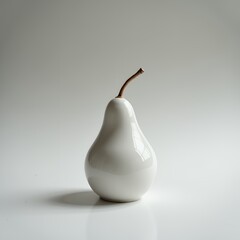 A white ceramic pear sits on a reflective surface, casting a soft shadow. Set against a light gray background, the scene feels minimalist and serene.