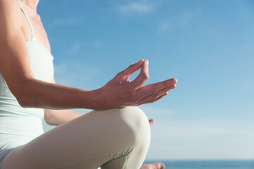 close up of a womans hands practicing yoga and meditating by the sea