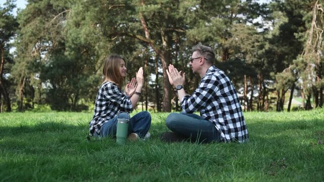 Father And Daughter Sitting On Grass In Summer Park Playing A Hand Clapping Game