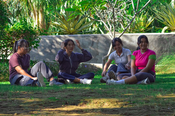 Four girls sit on the grass resting quietly, taking in the serene view of the garden around them...