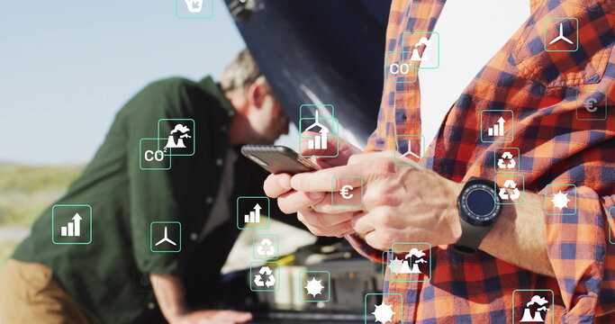 Man in orange and blue checkered shirt consulting smartphone at rural road, with engine components